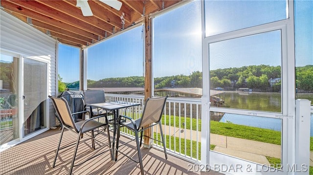 sunroom with ceiling fan, a water view, and a wealth of natural light