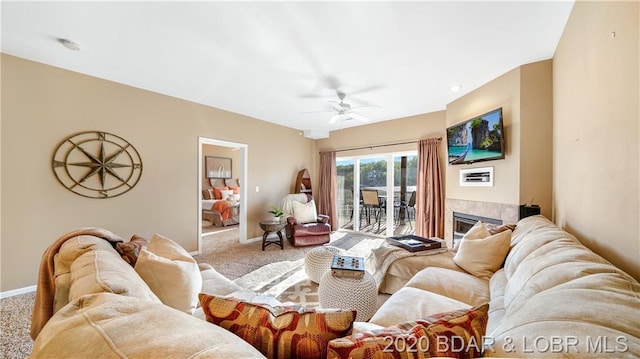 carpeted living room featuring a tiled fireplace and ceiling fan