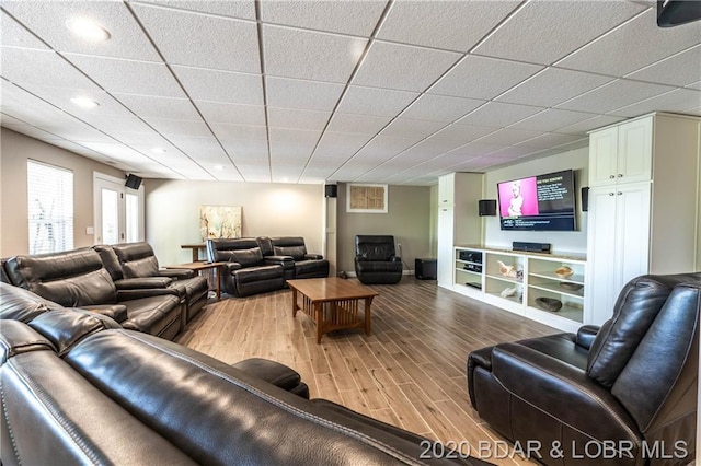 living room with light hardwood / wood-style flooring and a paneled ceiling