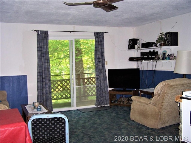 living room with ceiling fan, dark colored carpet, and a textured ceiling