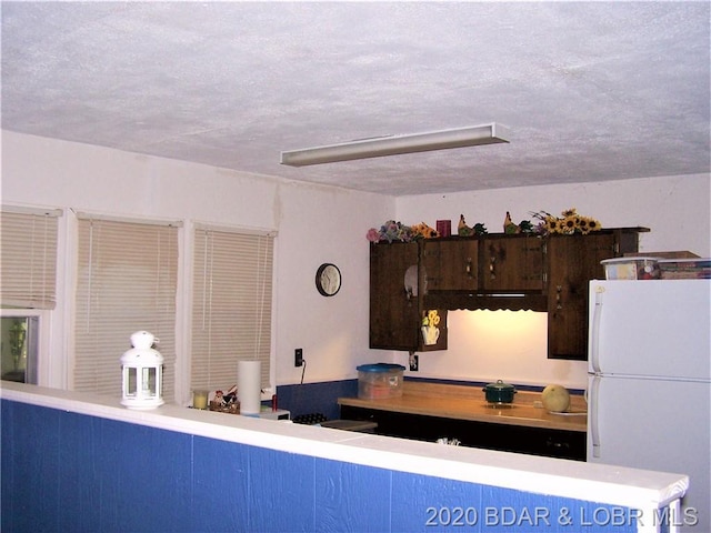 kitchen with white refrigerator and a textured ceiling