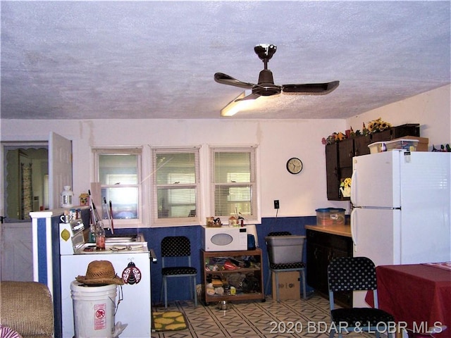 kitchen featuring ceiling fan, white appliances, a textured ceiling, and light tile floors