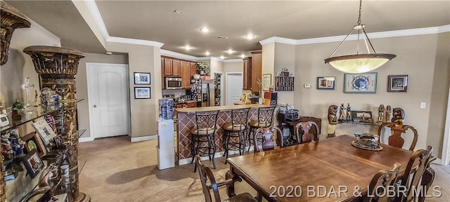 dining room featuring crown molding, bar area, and light tile floors