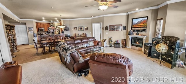 carpeted living room featuring ceiling fan and ornamental molding