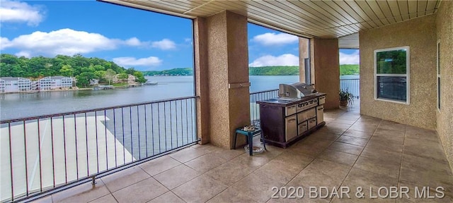 balcony with a water view, grilling area, and exterior kitchen