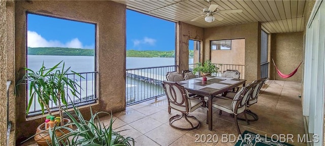 sunroom / solarium with ceiling fan, a water view, and plenty of natural light