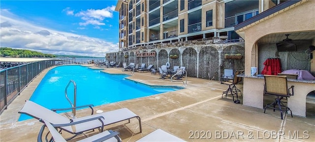 view of swimming pool featuring an outdoor bar, ceiling fan, and a patio