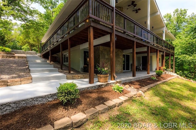 view of side of property with a wooden deck, a patio area, and ceiling fan