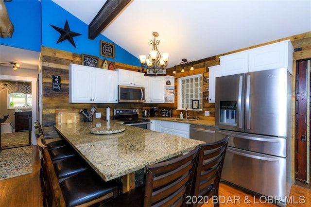 kitchen with dark hardwood / wood-style flooring, a breakfast bar, appliances with stainless steel finishes, a chandelier, and white cabinetry