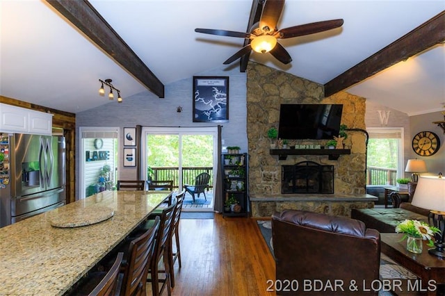 living room with vaulted ceiling with beams, ceiling fan, and a wealth of natural light