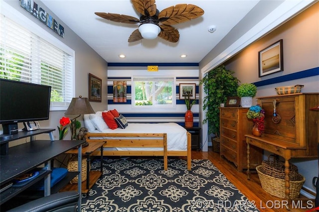 bedroom featuring ceiling fan, dark wood-type flooring, and multiple windows