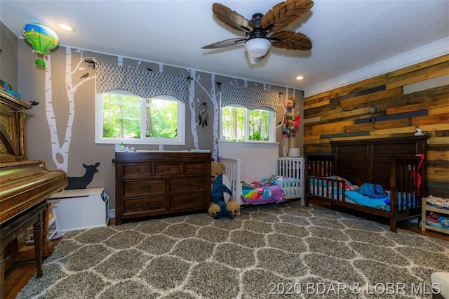 bedroom featuring ceiling fan and wood walls