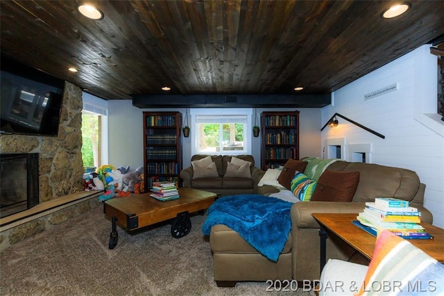 living room featuring wooden ceiling, carpet flooring, and a stone fireplace