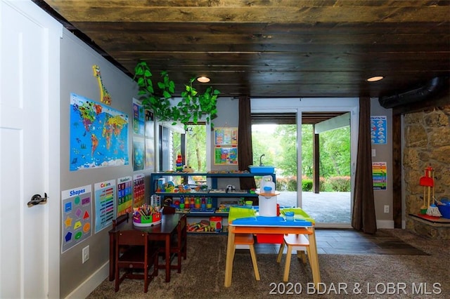 rec room featuring wooden ceiling and dark carpet