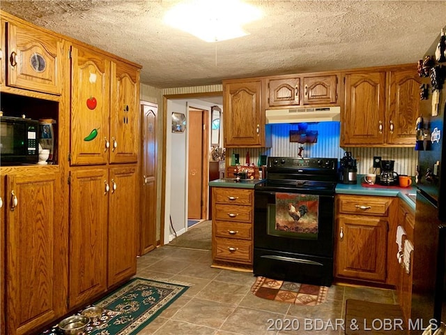 kitchen featuring tile flooring, black appliances, and a textured ceiling