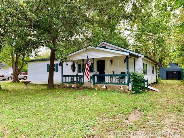 view of front of property featuring a front yard, a porch, and a storage shed