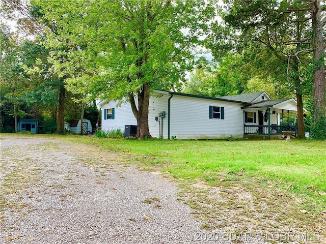 exterior space featuring a lawn, covered porch, and central air condition unit