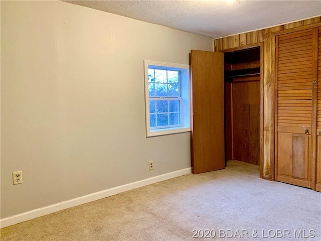 unfurnished bedroom with light carpet, a closet, and a textured ceiling