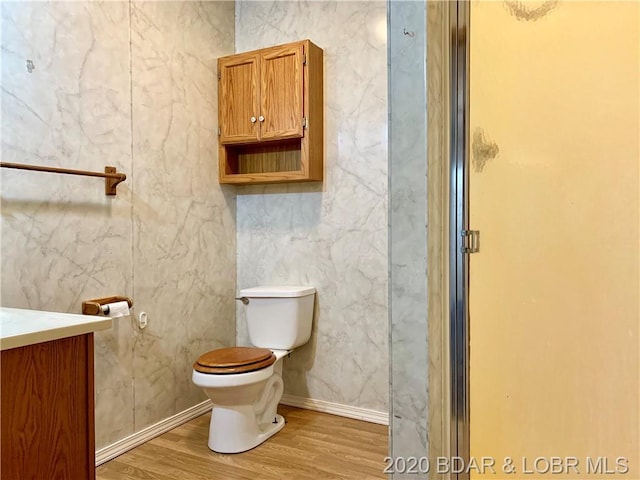 bathroom featuring a shower with door, toilet, vanity, and wood-type flooring