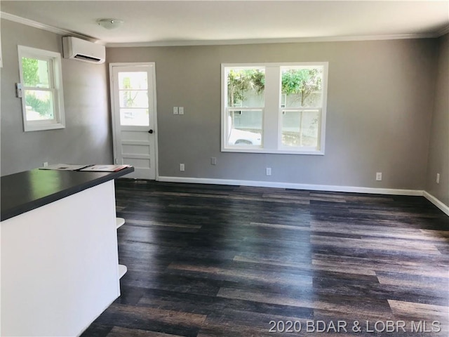 empty room featuring ornamental molding, dark wood-type flooring, and an AC wall unit