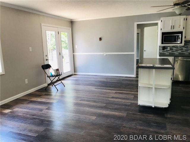 kitchen with dark hardwood / wood-style floors, tasteful backsplash, white cabinets, and appliances with stainless steel finishes