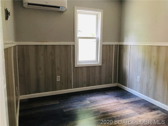 unfurnished room with dark hardwood / wood-style flooring and a wall mounted air conditioner