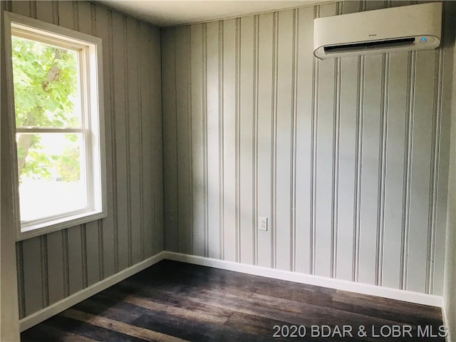 empty room with dark hardwood / wood-style flooring, a wall mounted AC, and a wealth of natural light