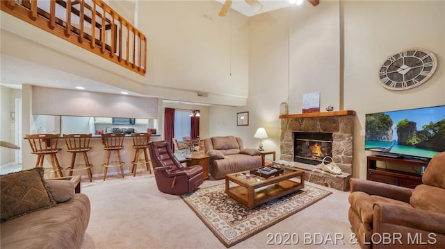 living room with light colored carpet, a fireplace, and a high ceiling