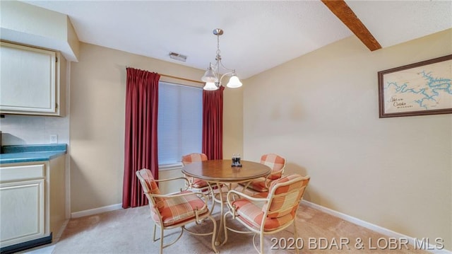 dining area with beam ceiling, an inviting chandelier, and light colored carpet