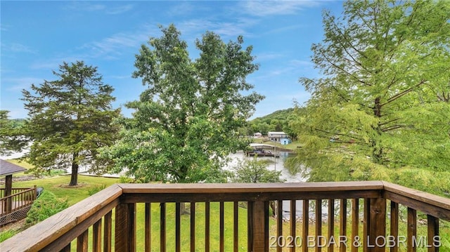 wooden terrace featuring a boat dock, a water view, and a yard