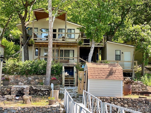 view of front of house with a balcony and a storage shed