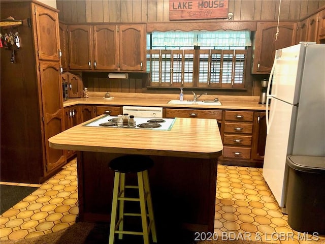 kitchen featuring white appliances, sink, light tile flooring, and wood counters