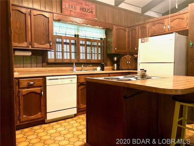 kitchen with light tile floors, a kitchen breakfast bar, white appliances, and sink