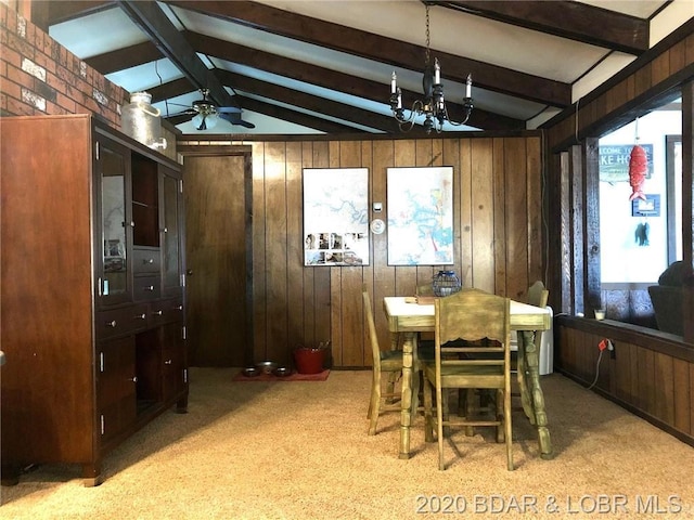 dining area with light carpet, wood walls, and ceiling fan with notable chandelier