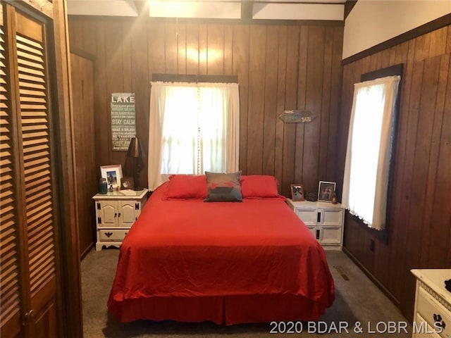 carpeted bedroom featuring wood walls