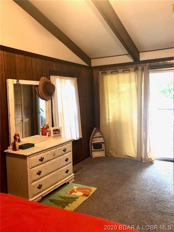 bedroom with dark carpet, multiple windows, and vaulted ceiling with beams