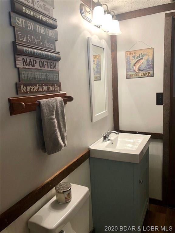 bathroom featuring a notable chandelier, vanity, a textured ceiling, and toilet