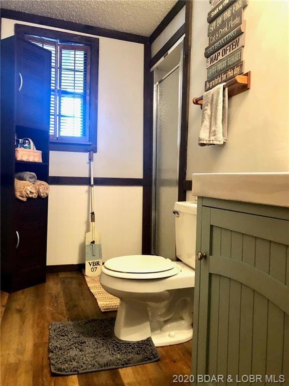 bathroom with wood-type flooring, toilet, vanity, and a textured ceiling