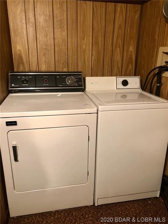 laundry room with washer and clothes dryer and wood walls