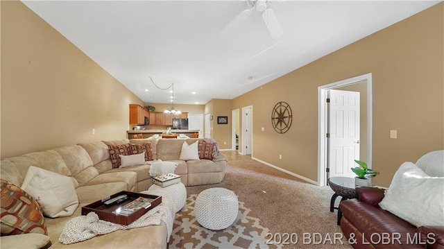 carpeted living room with ceiling fan with notable chandelier