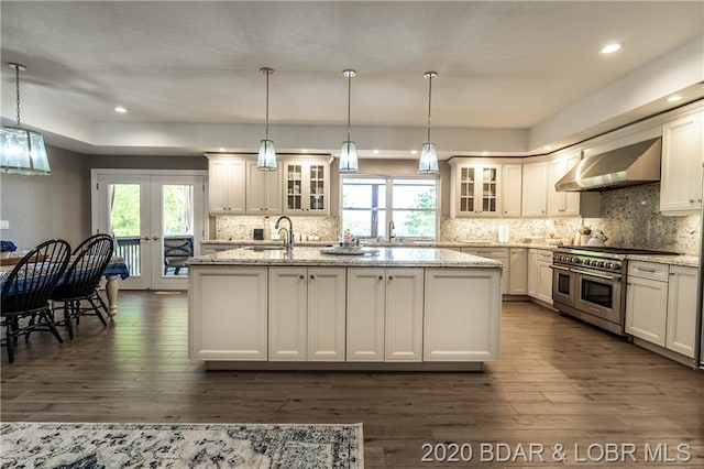 kitchen with decorative light fixtures, double oven range, wall chimney exhaust hood, french doors, and dark hardwood / wood-style flooring