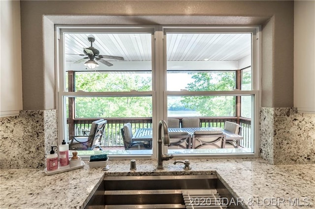 kitchen featuring sink, ceiling fan, and light stone counters