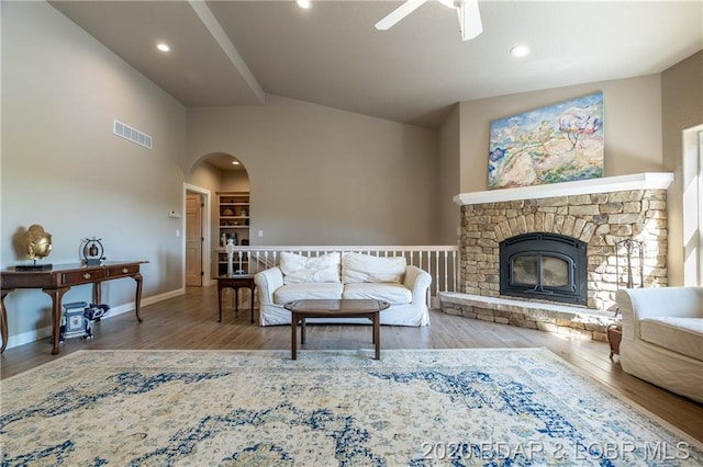 living room with a fireplace, high vaulted ceiling, ceiling fan, and light wood-type flooring