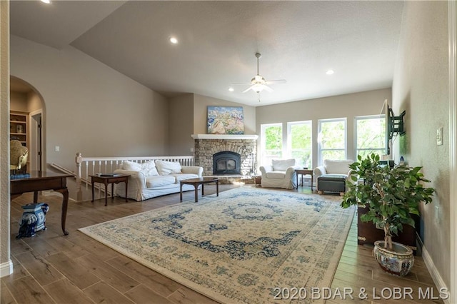 living room featuring lofted ceiling, dark hardwood / wood-style flooring, ceiling fan, and a fireplace