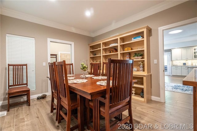 dining space with light wood-type flooring and ornamental molding