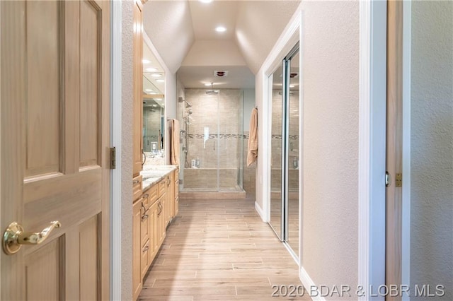 bathroom featuring lofted ceiling, walk in shower, vanity, and hardwood / wood-style flooring