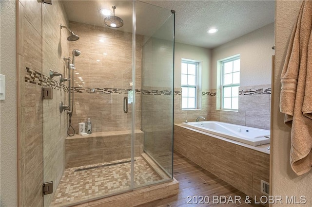 bathroom featuring hardwood / wood-style floors, a textured ceiling, and plus walk in shower