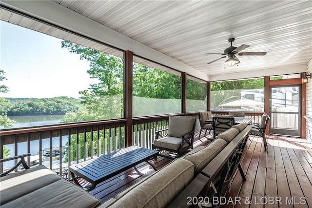 sunroom with ceiling fan and a water view