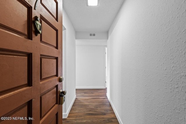 hallway with a textured ceiling and dark hardwood / wood-style floors