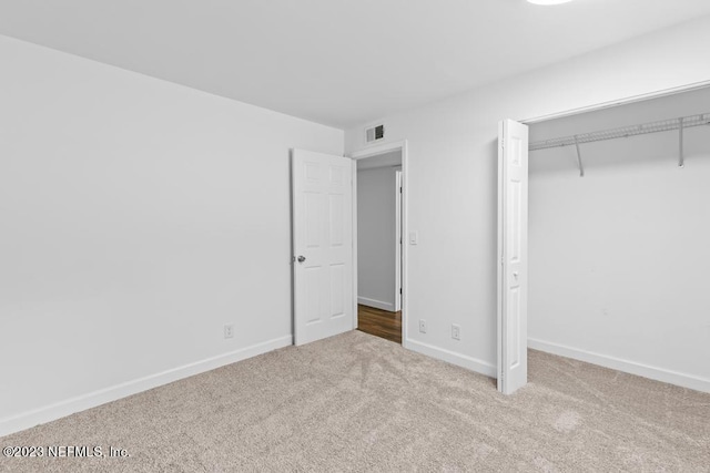 unfurnished bedroom featuring a closet and light colored carpet